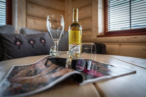a bottle of wine and a magazine on a wooden table at Good Morning Giewont & JACUZZI in Kościelisko