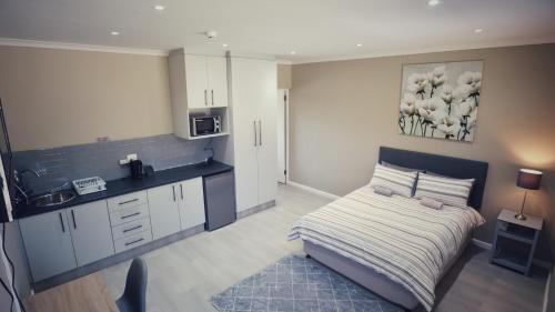 małą sypialnię z łóżkiem i kuchnią w obiekcie Guest Suite, Lorraine Port Elizabeth w mieście Lorraine