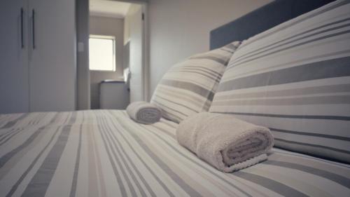 a bed with two towels and pillows on it at Guest Suite, Lorraine Port Elizabeth in Lorraine