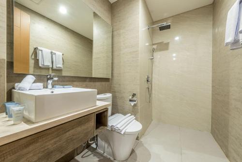 a bathroom with a toilet and a sink and a shower at Grande Valore Hotel Cikarang in Cikarang