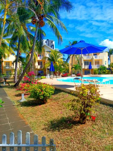 a resort with a pool and a blue umbrella at PRIM 29 in Flic-en-Flac