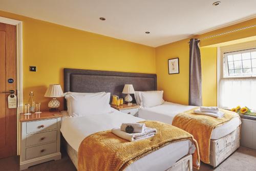 two beds in a bedroom with yellow walls at The Lansdowne Boutique Rooms with Breakfast - Adults Only in Bourton on the Water