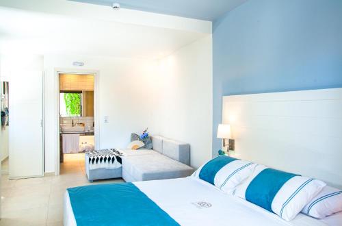 a bedroom with two beds and a couch in it at Acrotel Lily Ann Village in Nikiti