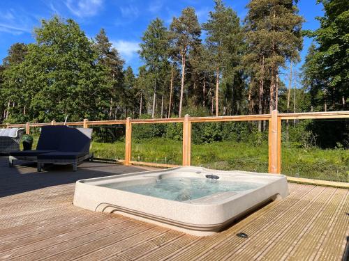 un bain à remous sur une terrasse en bois avec une chaise dans l'établissement Hollicarrs - Dragonfly Lodge, à York
