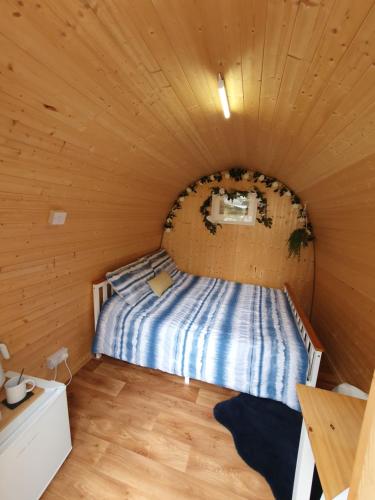 a bed in a room with a wooden ceiling at Gower Pods in Penclawdd