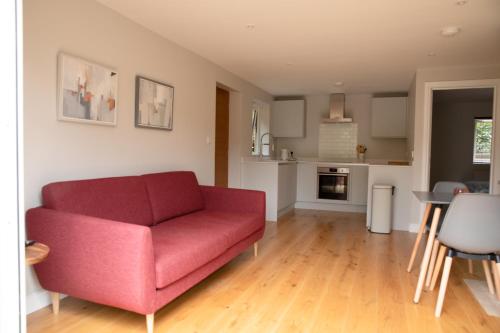 a living room with a red couch and a kitchen at Stylish one bed apartment in the Stroud Valleys in Brimscombe