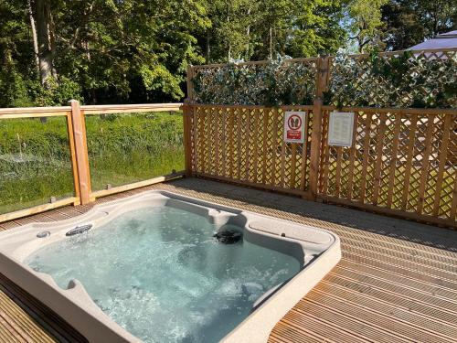 bañera de hidromasaje en una terraza con valla en Hollicarrs - Dragonfly Lodge en York
