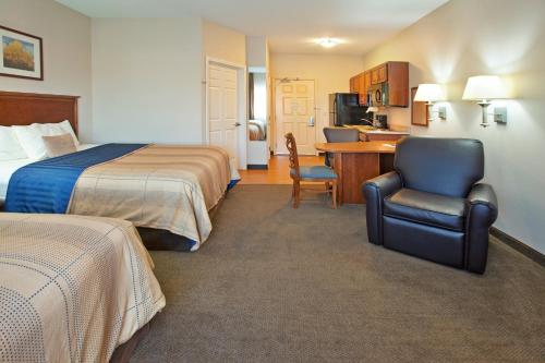 um quarto de hotel com duas camas, uma secretária e uma cadeira em Candlewood Suites Roswell, an IHG Hotel em Roswell