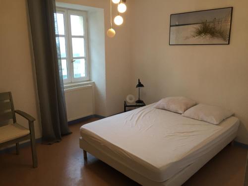 um quarto com uma cama, uma cadeira e uma janela em Agréable bastide provençale avec piscine em Barcelonne