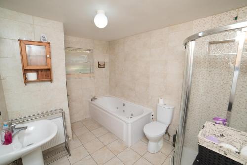 y baño con bañera, aseo y lavamanos. en Ballygown Cottage, en Torpys Cross Roads