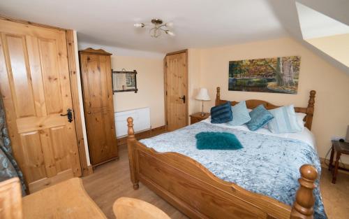 a bedroom with a wooden bed with blue pillows at Ballygown Cottage in Torpys Cross Roads