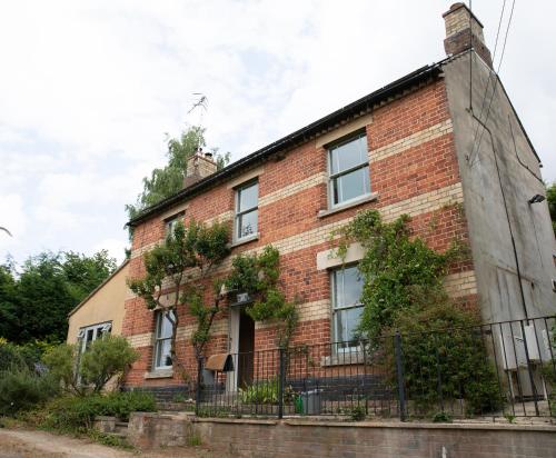 an old brick house with a fence in front of it at Stylish one bed apartment in the Stroud Valleys in Brimscombe