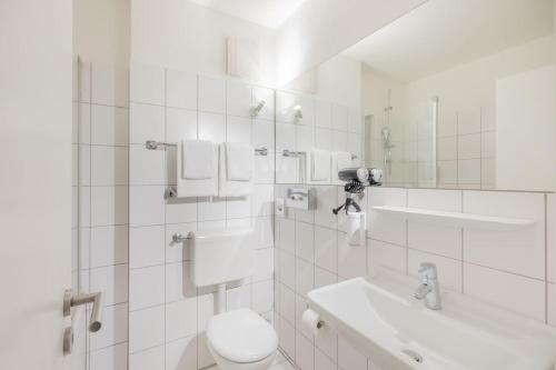 Baño blanco con aseo y lavamanos en Hotel Freiraum, en Mönchengladbach