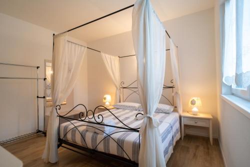 1 dormitorio con cama con dosel y cortinas blancas en La casa di Terlago, en Terlago