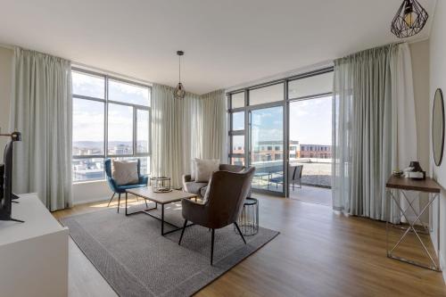 a living room with a table and chairs and windows at Axis Luxury Apartments by Century City Hotels in Cape Town
