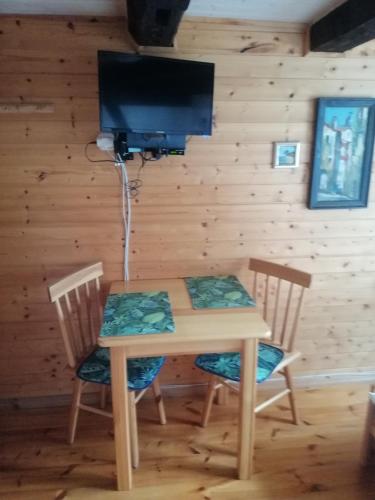 a wooden table and chairs with a television on a wall at Dom Gościnny Matysowka in Jarosławiec