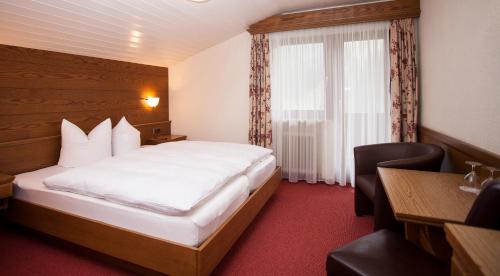 a hotel room with a bed and a desk and a window at Gasthof Talblick in Ischgl