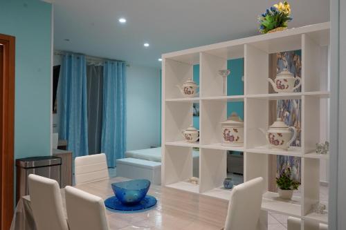 a room with a white shelf with vases and chairs at Casa di Suele in Solarino