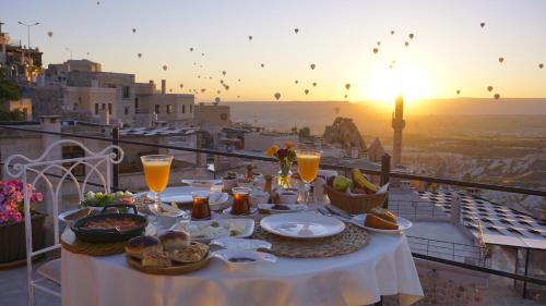 a table with food on a balcony with the sunset at Karlık Cave Suite Cappadocia in Uçhisar