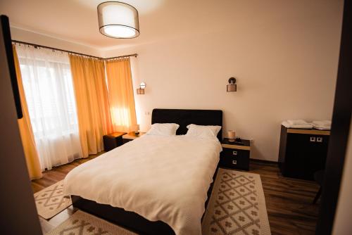 a bedroom with a large bed with white sheets at Agropensiunea turistică La Rusu in Rodna