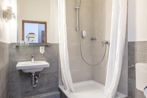 a bathroom with a sink and a shower at theAmbassador Hotel I Essen City in Essen