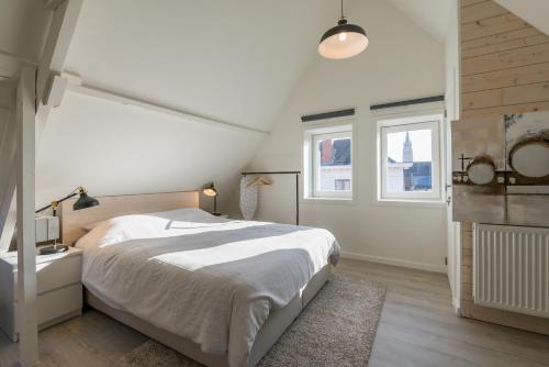 een witte slaapkamer met een bed en een raam bij Well Thirteen by Romy&Travis in Brugge