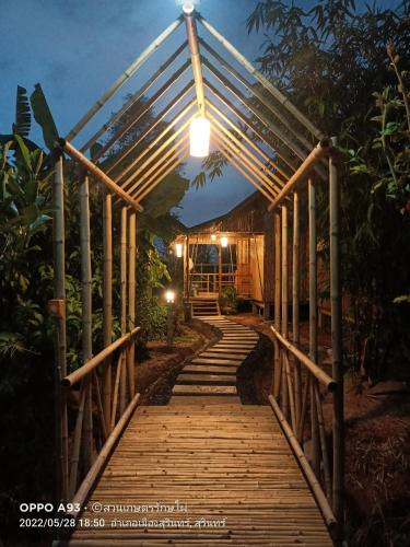 a wooden walkway leading to a house at night at สวนเกษตรรักษ์ไผ่ Bamboo Conservation Farm in Surin