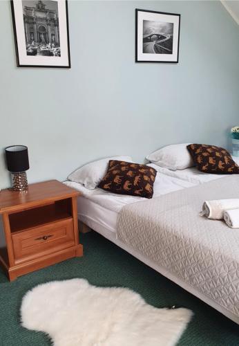 two beds in a room with a table and a white rug at ZibiSPA pokój nr 3 in Malbork