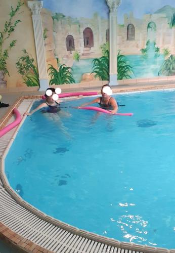 two people swimming in a swimming pool at ZibiSPA pokój nr 3 in Malbork