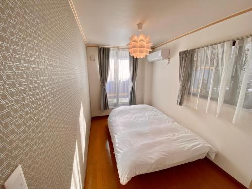 a small bedroom with a bed and a window at Villa Monica in Nagoya