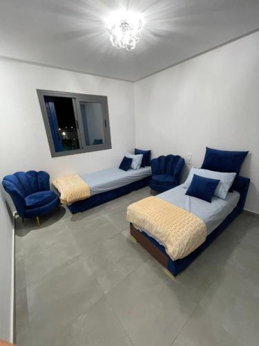 カボ・ネグロにあるNouveau complexe avec balcon et piscines privesのベッド2台と青い椅子2脚が備わる客室です。