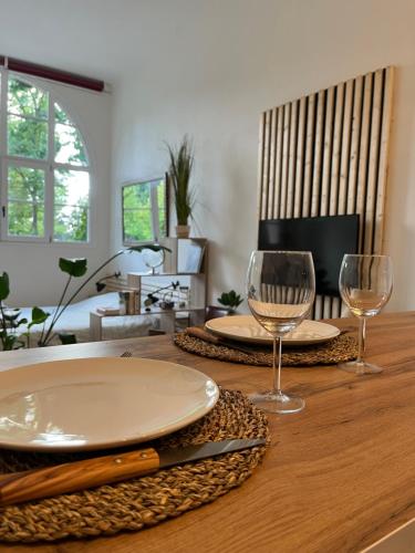 una mesa de madera con dos copas de vino. en Karma Loft Barbizon - 40m2, en Barbizon