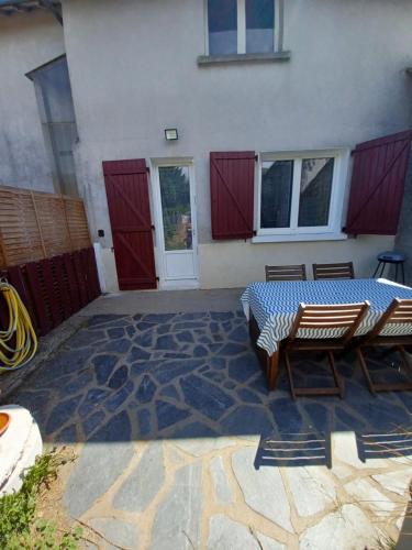 une terrasse avec une table et des chaises devant un bâtiment dans l'établissement GITE RURAL CHATAIGNERAIE CANTALIENNE, 