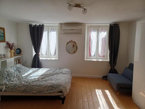 sypialnia z łóżkiem, kanapą i oknami w obiekcie GITE RURAL CHATAIGNERAIE CANTALIENNE 