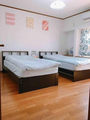 two beds in a room with wooden floors at Kyoto Nijo Traditional House in Kyoto