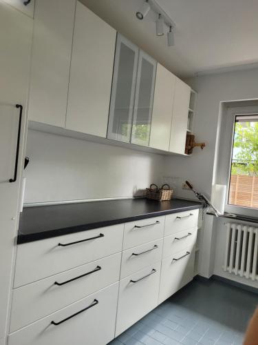 eine Küche mit weißen Schränken und einer schwarzen Arbeitsplatte in der Unterkunft Strandhaus Schilksee in Kiel