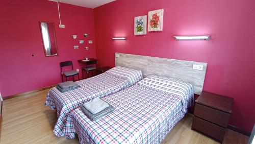 a bedroom with two beds and a pink wall at Family House Gijón in Gijón