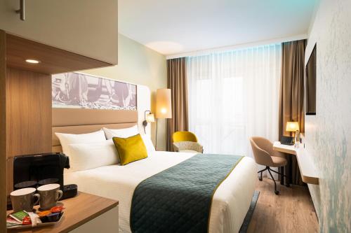 a hotel room with a bed and a desk at Leonardo Hotel Hamburg Altona in Hamburg