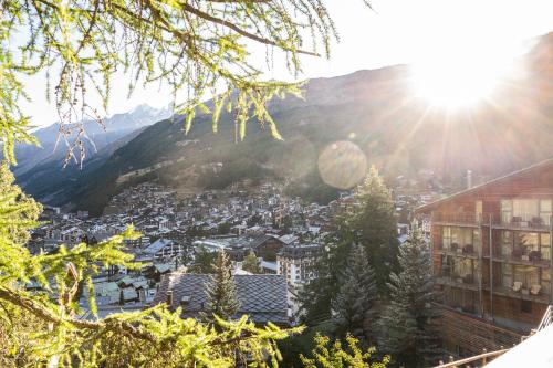 a view of a town in the mountains with the sun at Studio direkt im Zentrum, tolle Terrasse, Aussicht in Zermatt