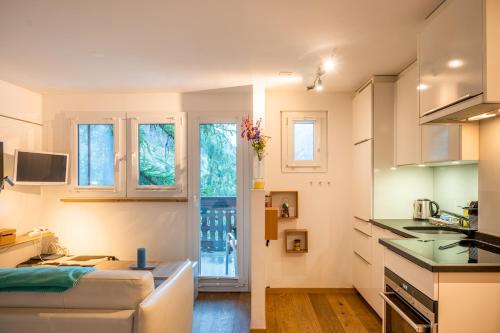 a kitchen and living room with white cabinets and a couch at Studio direkt im Zentrum, tolle Terrasse, Aussicht in Zermatt