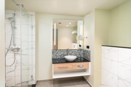 a bathroom with a sink and a shower at Leonardo Hotel Hamburg Altona in Hamburg