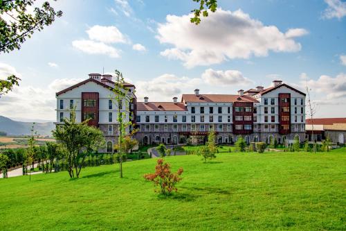 a large building with a green field in front of it at Basqal Resort & SPA in Basqal