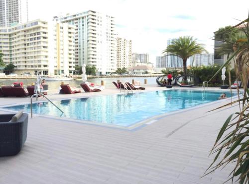 a large swimming pool with lounge chairs and buildings at Sunlit BeachWalk Studio 2 Full Beds Coastal Charm -26B in Hallandale Beach