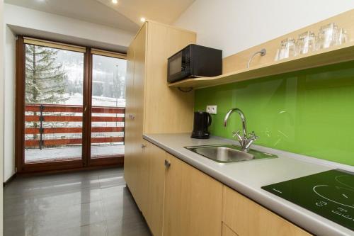 cocina verde con fregadero y ventana en Apartament przy Dolinie A8 by Apart Concept Podhale en Kościelisko