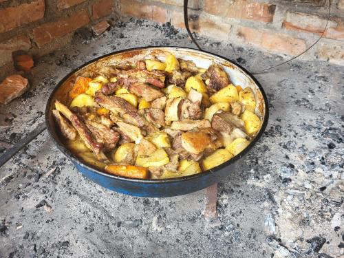 a pan of food with meat and potatoes in it at Kamp Bungalovi Sase drvena kuca in Višegrad