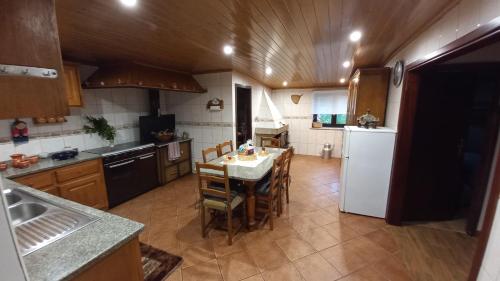 a kitchen with a table and a white refrigerator at Casa da Rosa Porreiras in Paredes de Coura