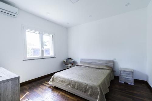 - une chambre blanche avec un lit et une fenêtre dans l'établissement Tropical House, à San Leonardello