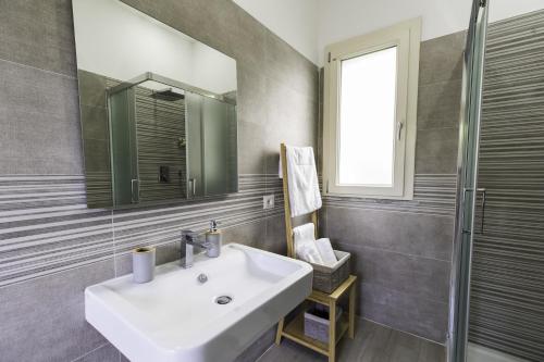 La salle de bains est pourvue d'un lavabo blanc et d'un miroir. dans l'établissement Tropical House, à San Leonardello