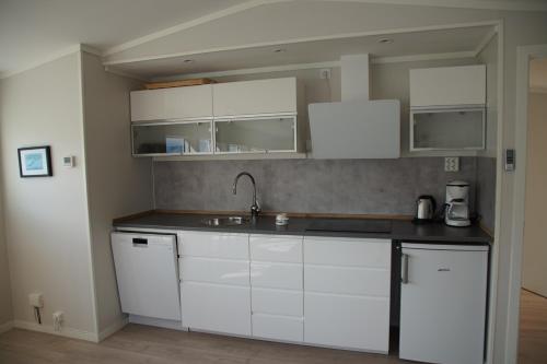 a kitchen with white cabinets and a sink at Frugga Feriehus og leilighet in Straumsjøen