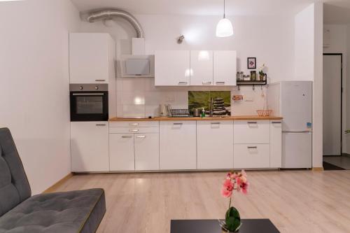 a kitchen with white cabinets and a vase of flowers on a table at FIRST - Green Żoliborz Apartment 6 in Warsaw